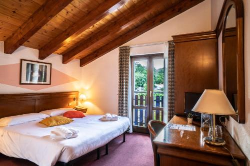 una camera da letto con un letto, una scrivania e una finestra di Hotel Castello a Montjovet