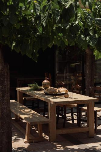 a wooden picnic table with two plates of food on it at Phāea Cretan Malia, a Member of Design Hotels in Malia