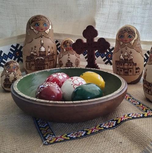 a bowl of easter eggs on a table with a cross at Căsuța de chirpici in Dunăvăţul-de-Sus