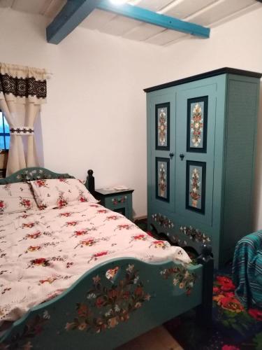 a bedroom with a green bed and a cabinet at Căsuța de chirpici in Dunăvăţul-de-Sus