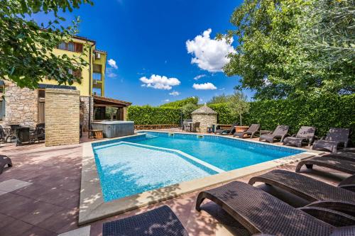 une piscine avec des chaises longues à côté d'un bâtiment dans l'établissement Villa Bucks near Poreč for 20 persons with Sea View, Whirlpool, Sauna & Fitness, à Višnjan