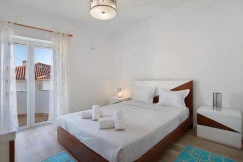 a bedroom with a white bed with a large window at Praia Azul Beach and Sun in Silveira