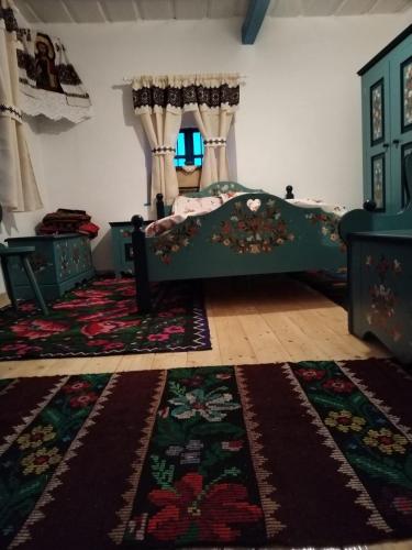 a bedroom with a bed and two rugs at Căsuța de chirpici in Dunăvăţul-de-Sus