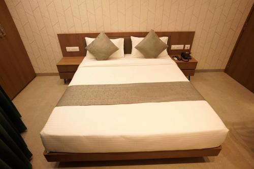 a bedroom with a bed with white sheets and pillows at A Square Executive Hotel in Aurangabad