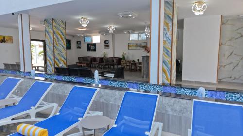 a swimming pool with blue and white chairs in front of it at Golden Hotel in Nungwi