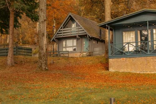 a house in the woods with leaves on the ground at Crieff Hydro Self Catering in Crieff