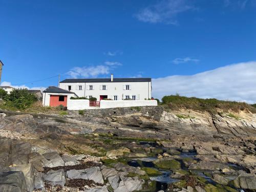 a white building on top of a rocky cliff at Casa costa de Lugo frente al mar in Nois