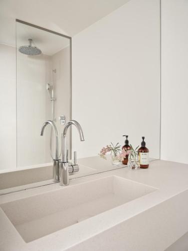 a white sink in a bathroom with a mirror at Bob W Munich Schwabing in Munich