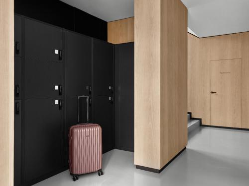 a red suitcase in a room with black cabinets at Bob W Munich Schwabing in Munich