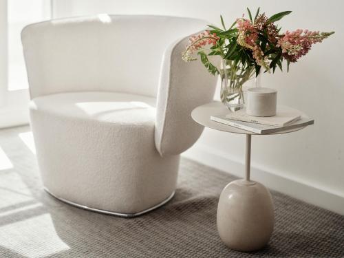 a white chair and a table with a vase of flowers at Bob W Munich Schwabing in Munich