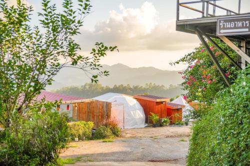 a group of tents in a yard with flowers at อาฉ่างแคมป์ Achang Camp in Mon Jam