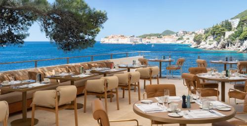 Un restaurante con mesas y sillas y el océano. en Villa Dubrovnik, en Dubrovnik