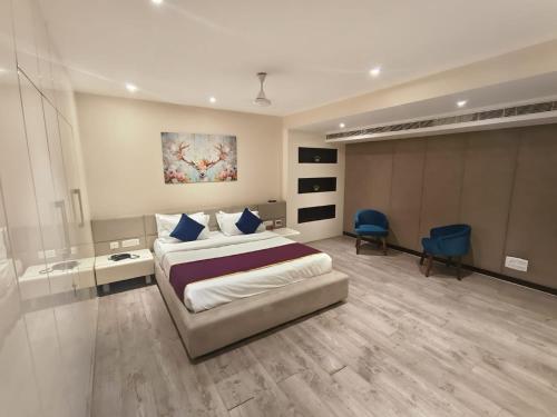 a bedroom with a large bed and a blue chair at Vilva Town House in Chennai