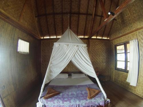 a bed in a room with a mosquito net at Abdi Fantastik in Gili Air