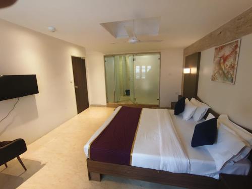 a bedroom with a large bed and a television at Vilva Town House in Chennai