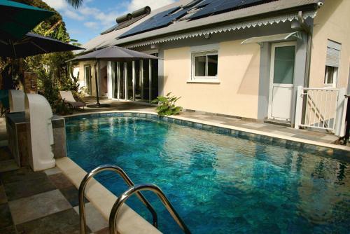 a swimming pool in front of a house at O'Meublés des 2Bois- Le Filao-Piscine chauffée & Spa in Le Tampon