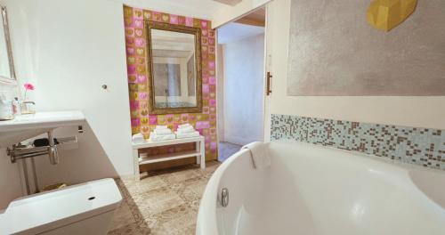 a bathroom with a tub and a sink and a mirror at AjoieSpa in Porrentruy