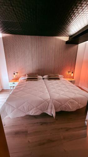 a large white bed in a room with two lamps at Apartamentos villa Carolina in Porriño