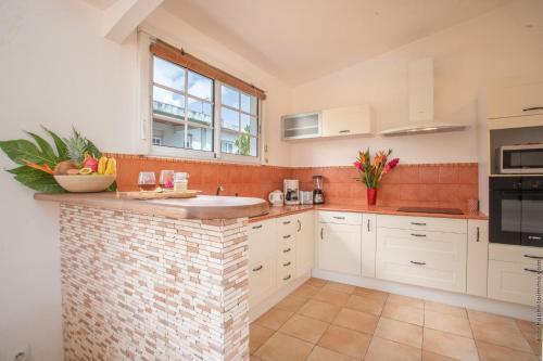 a kitchen with white cabinets and a brick wall at Coconut Bay House avec Piscine et Jacuzzi in Le Robert