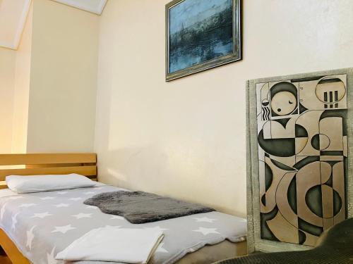 a bedroom with a bed and a picture on the wall at Lovely Garden 100m2 apartment in Novi Sad