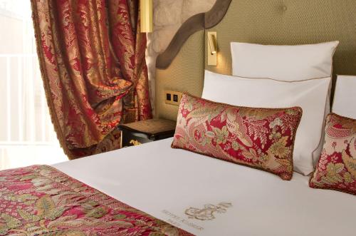 a hotel room with a bed with red and white pillows at Hôtel Kleber Paris & Spa in Paris