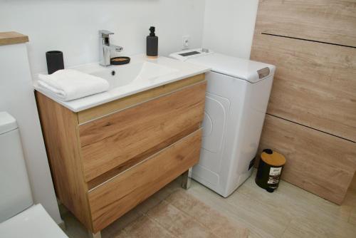 a bathroom with a sink and a washing machine at O'Meublés des 2Bois- Le Filao-Piscine chauffée & Spa in Le Tampon
