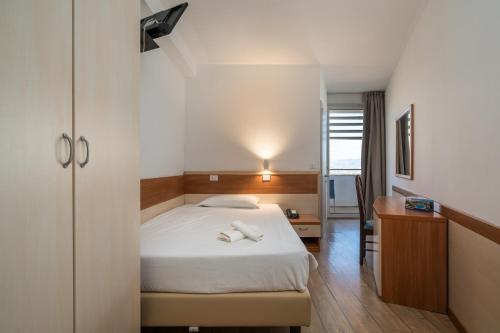 a bedroom with a bed and a desk with two shoes on it at Hotel Centro Turistico Gardesano in Bussolengo