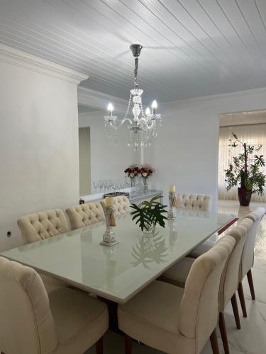 a dining room with a white table and a chandelier at Refúgio na Capital in Curitiba