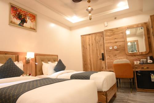 a hotel room with two beds and a desk at Hotel Kashi Crown in Varanasi