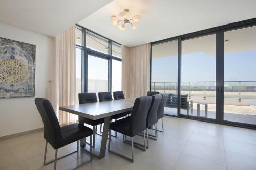 a dining room with a table and chairs and windows at Silk Valley - 4B near Al Hamriyah | private beach access in Sharjah