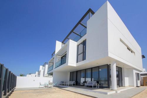 a white building with tables and chairs in front of it at Silk Valley - 4B near Al Hamriyah | private beach access in Sharjah