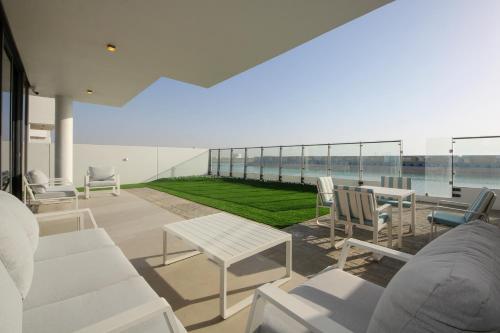 a patio with white furniture and a view of the water at Silk Valley - 4B near Al Hamriyah | private beach access in Sharjah