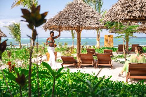 a woman walking on the beach at a resort at Clove Island Essence & Spa Boutique in Matemwe
