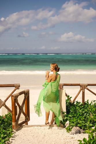 a woman in a green dress standing on the beach at Clove Island Essence & Spa Boutique in Matemwe