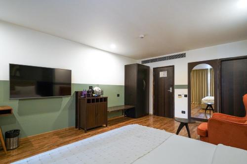 a bedroom with a bed and a television and a chair at Olive Hotel MG Road Dunsvirk Inn by Embassy Group in Bengaluru