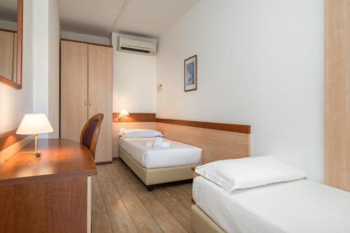 a hotel room with two beds and a desk at Hotel Centro Turistico Gardesano in Bussolengo