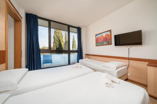 a hotel room with two beds and a flat screen tv at Hotel Centro Turistico Gardesano in Bussolengo