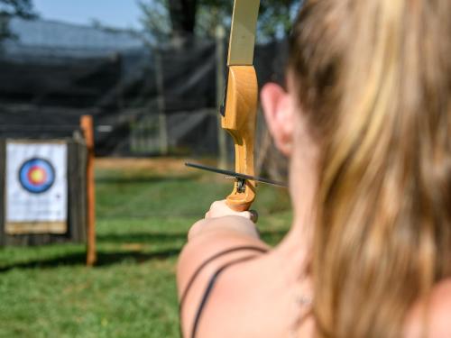 a woman holding a bow and arrow in front of a target at Cayley Mountain Resort in Champagne Valley