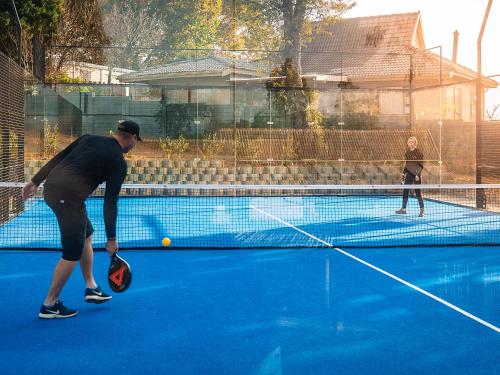 two men playing tennis on a tennis court at Cayley Mountain Resort in Champagne Valley