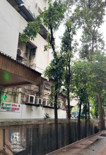 a white building with trees in front of it at Hotel Comfort Castle in Mumbai