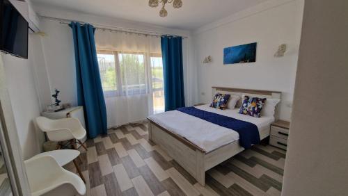 a bedroom with a bed with blue curtains and a window at Sweet Desire in Vama Veche