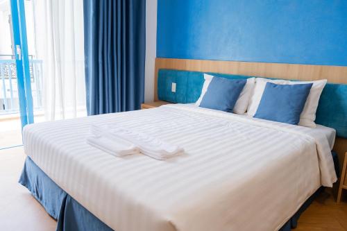 a bedroom with a large white bed with blue walls at Turi Staypoint in Quang Ngai
