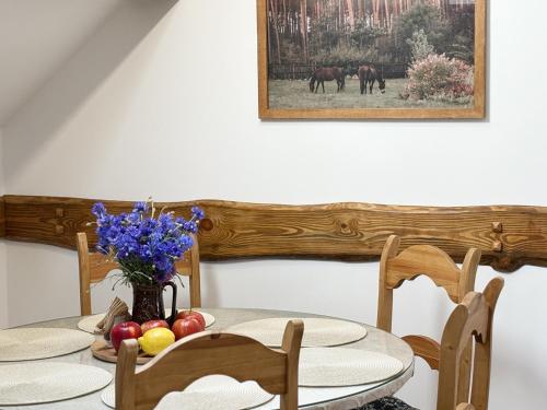 a table with two chairs and a vase of flowers at Nocleg na skraju puszczy in Ludomy