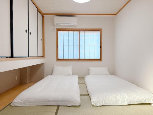 two beds in a room with two windows at Tsukisucho, 4 bedrooms, 1 Japanese style room, 4LDK, Namba, Nihonbashi, Tsutenkaku house, free parking, elevator in Osaka
