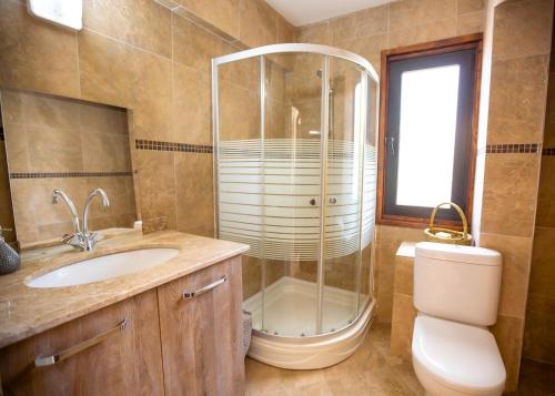 a bathroom with a shower and a sink and a toilet at Luxurious Villa Beckham by HolidayKeys in Kérynia