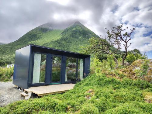 a black house on a hill with a mountain at Rystad Lofoten Camping in Rystad