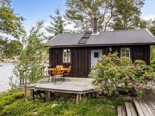 a cabin by the water with a table and chairs on a wooden deck at Holiday Home Huset på Udden by Interhome in Söderhamn