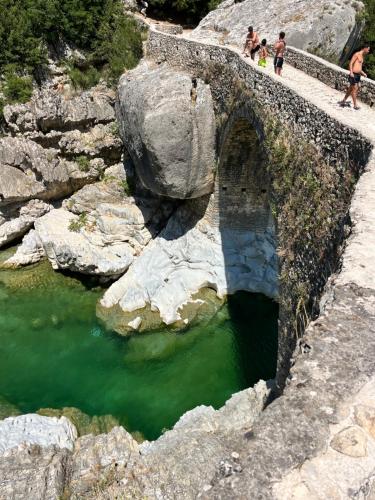 a bridge over a river with people walking over it at Room for Rent in Brataj