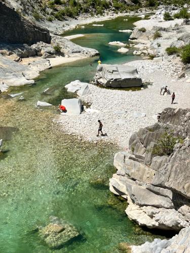 people walking on a rocky beach next to a river at Room for Rent in Brataj