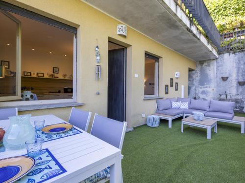 Un patio con una mesa y sillas y un sofá. en Apartment Il Gianlupo Azzurro by Interhome, en Belgirate